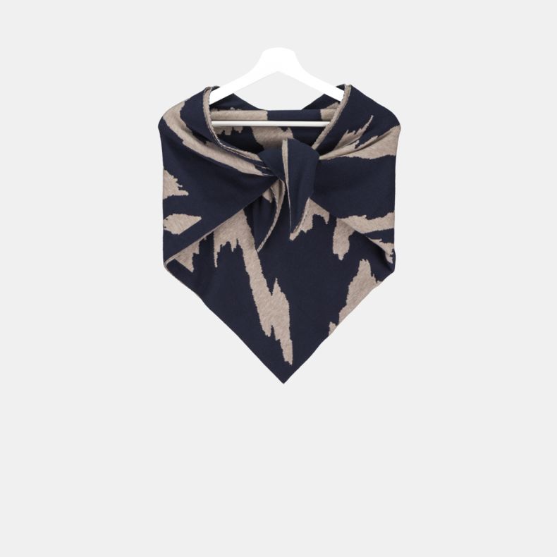 Navy and beige triangular knitted scarf with a bold abstract pattern, soft fine-knit texture, and wrap-around design, displayed tied at the front on a hanger from a wider front view for stylish cold-weather layering.