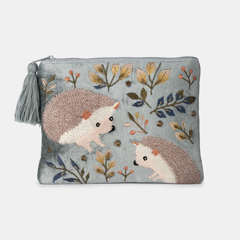 Light blue velvet cosmetic pouch with embroidered hedgehog design, featuring woodland leaves, berry motifs, bead embellishments, zip-top closure, and decorative tassel pull.