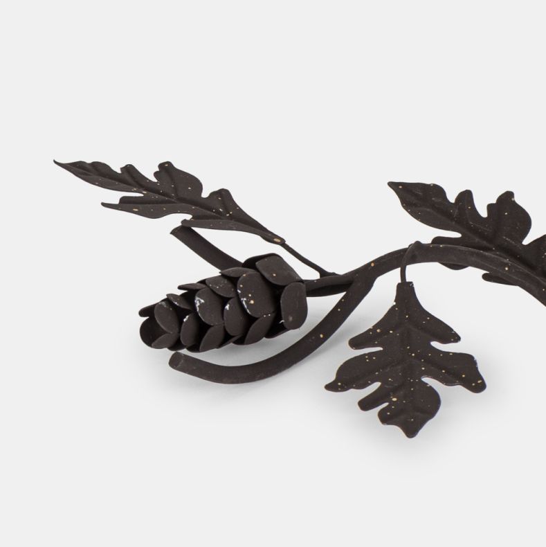 Rustic metal candle holder close-up, highlighting the textured pine cone and oak leaf details, dark aged finish, and woodland-inspired branch design with decorative gold-effect speckling.