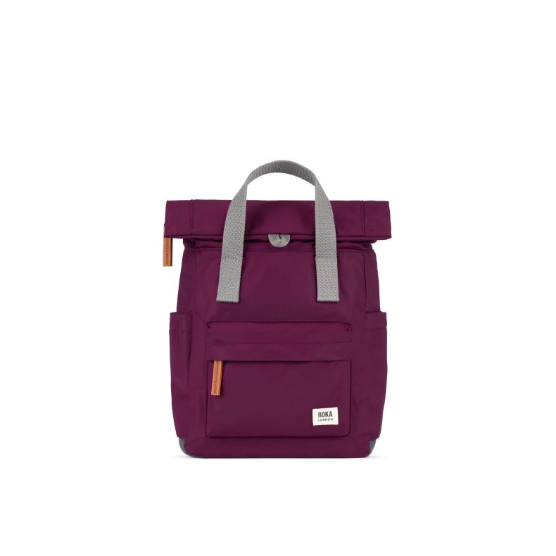Burgundy red Roka London backpack with a roll-top closure, grey webbing carry handles, front zip pocket, side pockets, and tan zip pulls. The lightweight backpack features a minimalist design and Roka London logo label on the front.