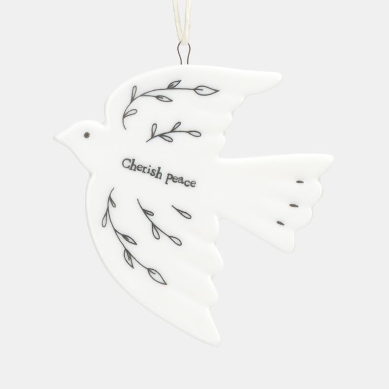 White ceramic dove Christmas hanging decoration shown in a close-up view, featuring delicate black botanical line illustrations, the words “Cherish peace”, a smooth glazed finish, and a cream hanging ribbon for festive seasonal décor.