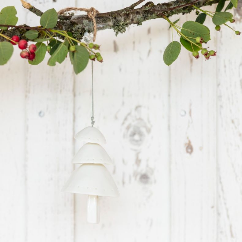 White ceramic Christmas tree hanging decoration displayed on a natural branch, featuring a layered tiered tree design with subtle pierced dot detailing, a smooth glazed finish, and a silver hanging cord, styled as a festive seasonal ornament.