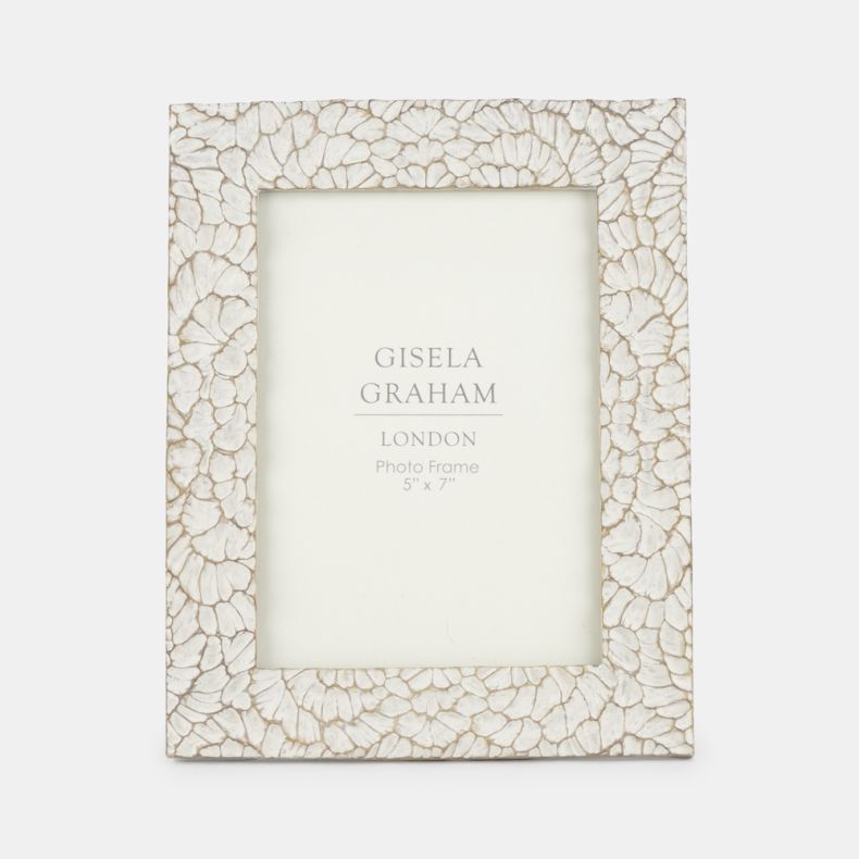 Decorative photo frame featuring an intricate shell-inspired mosaic pattern in soft cream tones with subtle distressed detailing. Designed to display a 5" x 7" photograph, the textured frame adds natural elegance and coastal-inspired charm to shelves, sid