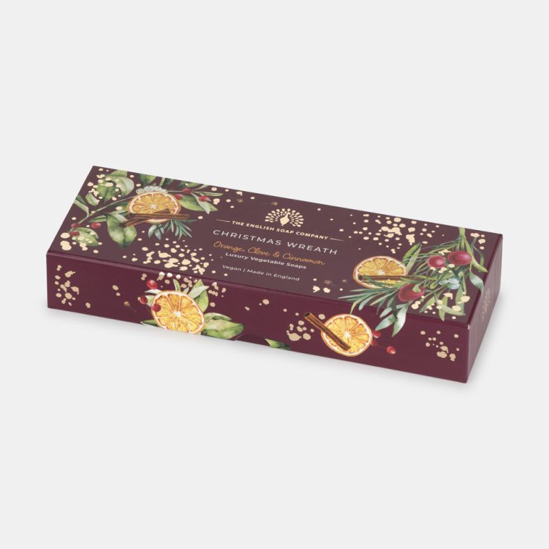 Gift box containing Christmas Wreath luxury vegetable soaps, decorated with festive illustrations of dried orange slices, cinnamon sticks, berries, greenery and gold accents. Scented with orange, clove and cinnamon, vegan and made in England.