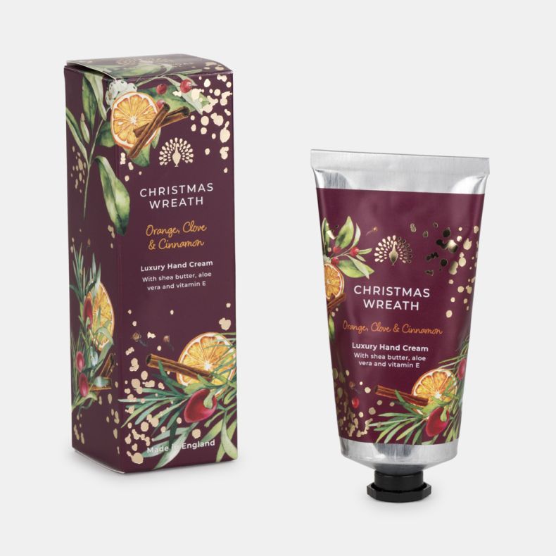 Christmas Wreath luxury hand cream tube and matching gift box in festive burgundy packaging with dried orange slices, cinnamon sticks, berries, greenery and gold accents. Fragranced with orange, clove and cinnamon, enriched with shea butter, aloe vera and