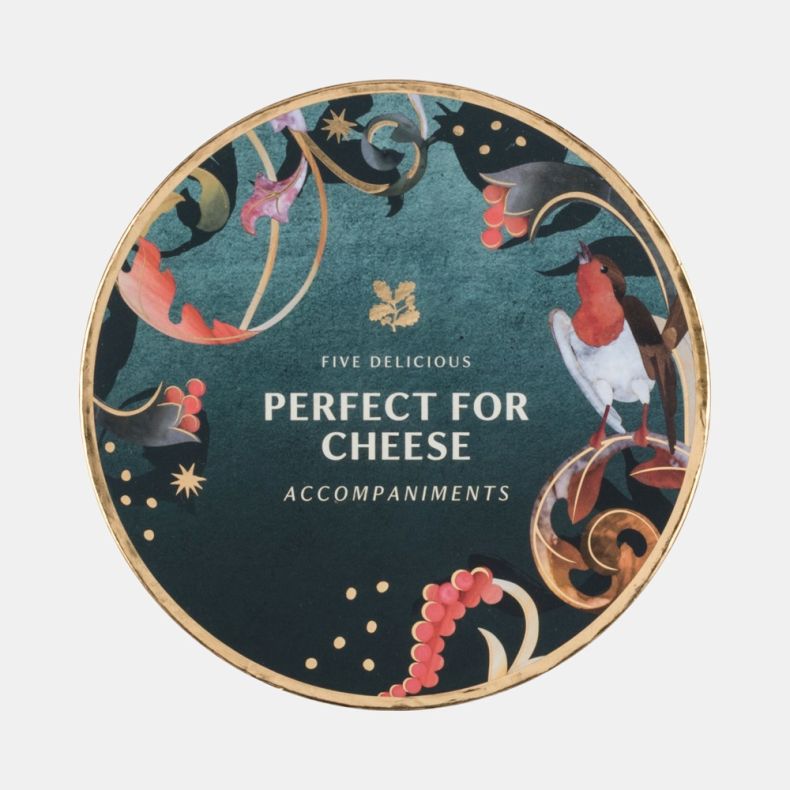Close-up of the decorative lid from a cheese accompaniments gift tin, featuring a dark green festive design with a robin illustration, holly berries, foliage, gold accents and the text “Five Delicious Perfect for Cheese Accompaniments”, isolated on a whit