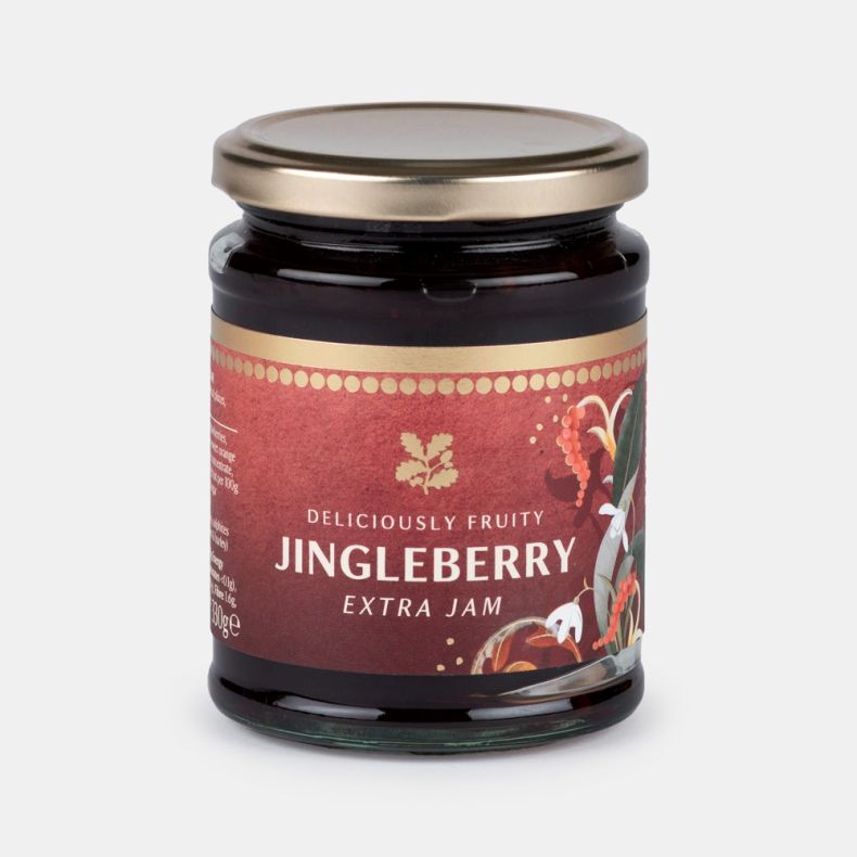 Jar of deliciously fruity jingleberry extra jam, featuring a clear glass jar with a gold lid and a burgundy label decorated with festive botanical artwork, showing dark berry jam inside and isolated on a white background.