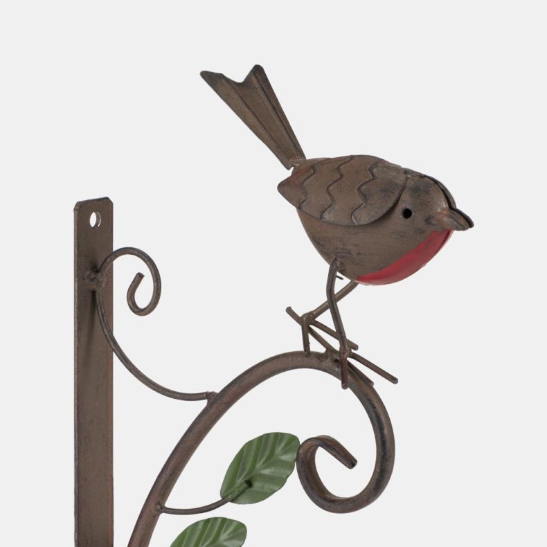Close-up of a decorative metal robin wall bracket with a rustic brown finish and bright red breast. The robin perches on a curved scrollwork arm with green leaf accents, designed for hanging baskets, lanterns, or other garden decorations.