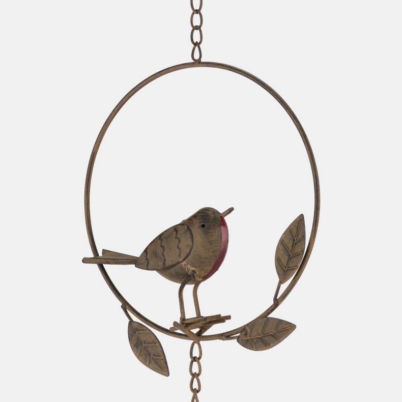 Close-up of a decorative metal robin wind chime featuring a rustic brown robin with a red breast perched inside a circular ring. The hanging ornament is accented with embossed metal leaves and suspended from a chain for garden or outdoor display.
