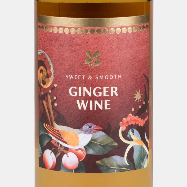 Close-up of a sweet and smooth ginger wine bottle label featuring a bird, cherries, festive foliage and the text “Sweet & Smooth Ginger Wine”.