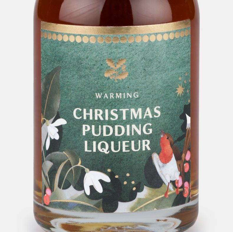 Close-up of a warming Christmas pudding liqueur bottle label featuring a robin, winter foliage, berries and the text “Warming Christmas Pudding Liqueur”.