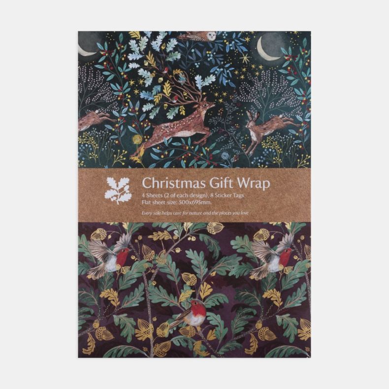Christmas gift wrap set featuring two festive wrapping paper designs, including a woodland scene with a stag, hare and owl beneath a moonlit sky, and a robin-and-acorn pattern on a deep purple background, presented with a kraft paper band labelled “Christ