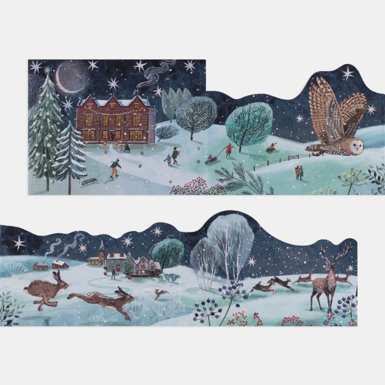 Freestanding advent calendar fully opened to reveal a panoramic winter landscape, featuring snowy countryside scenes with a grand house, village cottages, deer, hares, an owl in flight, skaters, sledders and snow-covered trees beneath a star-filled night 