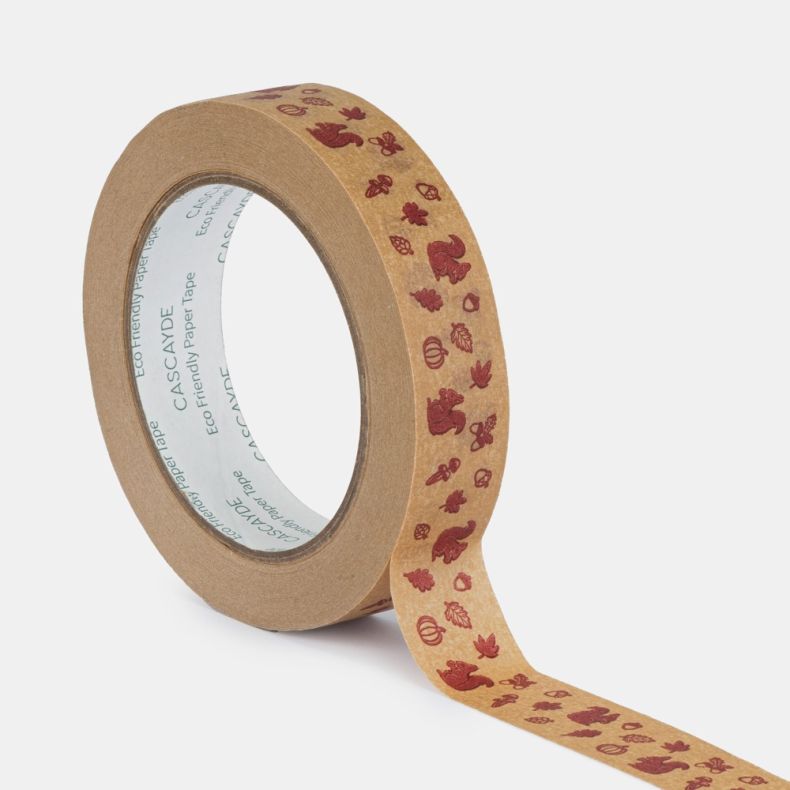 Roll of eco-friendly paper tape shown with a length unfurled, featuring a repeating autumn woodland design with burgundy illustrations of squirrels, acorns, oak leaves, mushrooms, pumpkins and pinecones printed on a natural kraft paper background, isolate