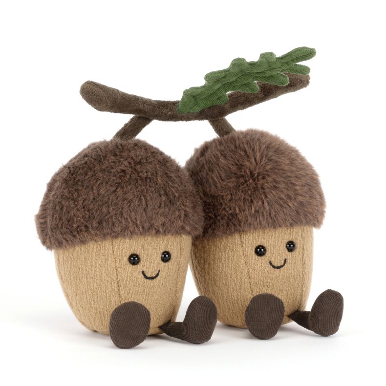 Jellycat acorn soft toy featuring two smiling plush acorns joined by a soft branch with green oak leaves. The cuddly woodland duo has fluffy brown caps, tan bodies, corduroy legs and embroidered facial details.