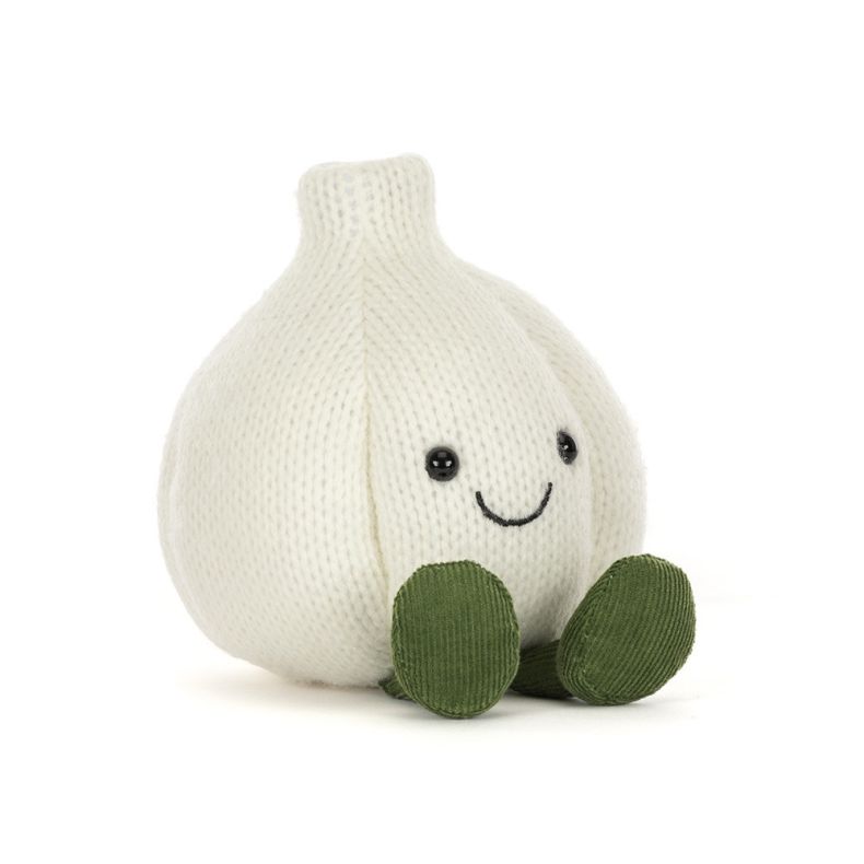 Angled view of White knitted garlic bulb plush toy with a smiling face, black button eyes, and green corduroy feet, photographed against a light grey background.