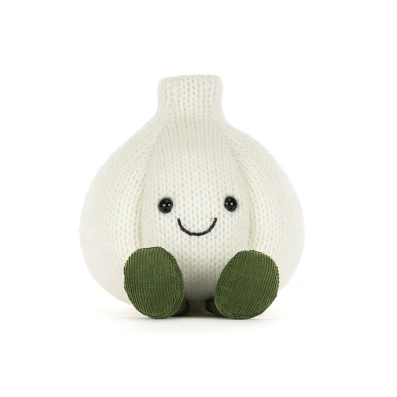Front view of White knitted garlic bulb plush toy with a smiling face, black button eyes, and green corduroy feet, photographed against a light grey background.