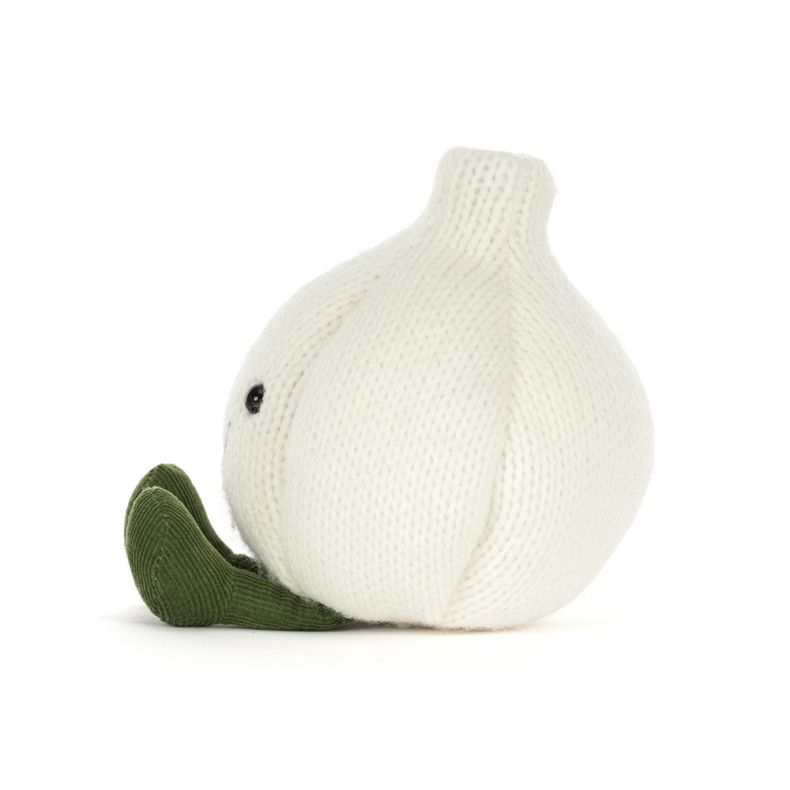Side view of White knitted garlic bulb plush toy with a smiling face, black button eyes, and green corduroy feet, photographed against a light grey background.