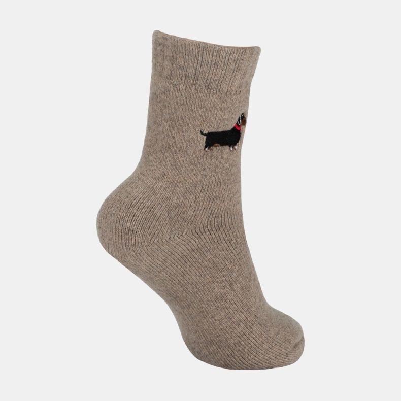 Light brown ankle sock with a soft marl texture and ribbed cuff, featuring an embroidered black and tan dachshund motif with a red collar on the outer ankle, shown from an angled side view against a white background.
