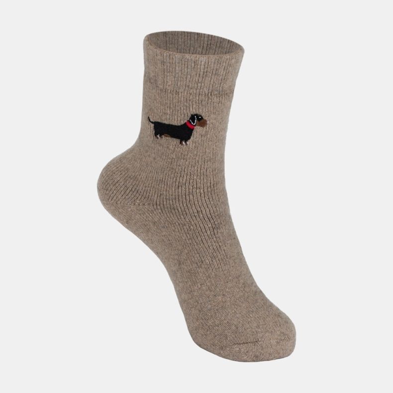 Light brown ankle sock with a soft marl texture and ribbed cuff, featuring an embroidered black and tan dachshund motif with a red collar on the outer ankle, displayed against a white background.