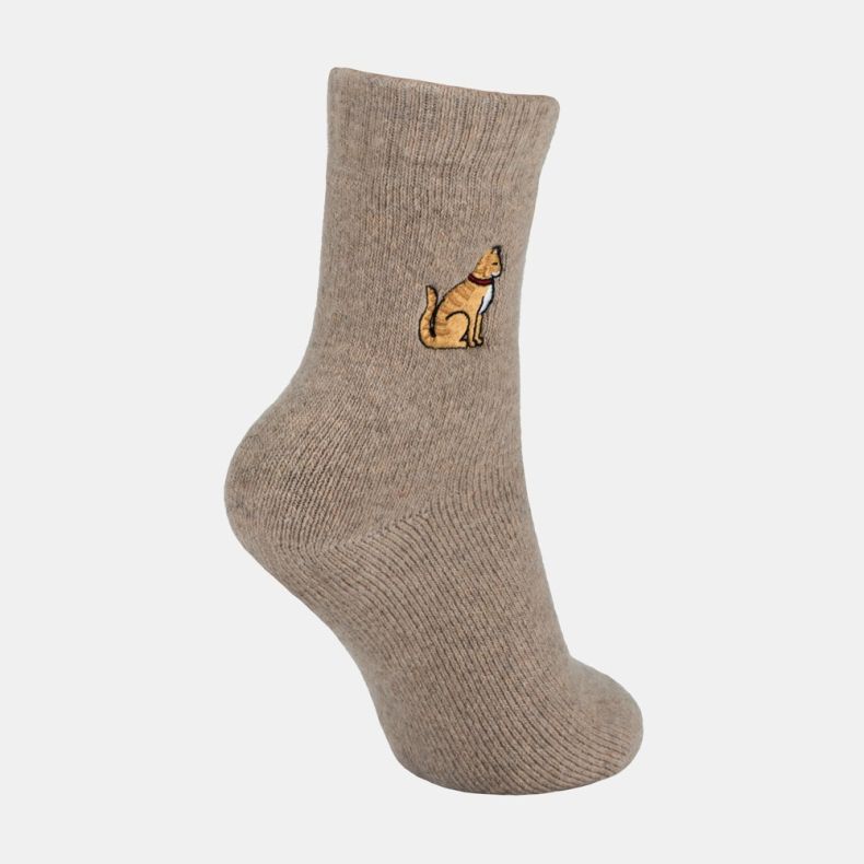 Light brown ankle sock with a soft marl texture and ribbed cuff, featuring an embroidered golden dog motif with a red collar on the outer ankle, shown from an angled side view against a white background.