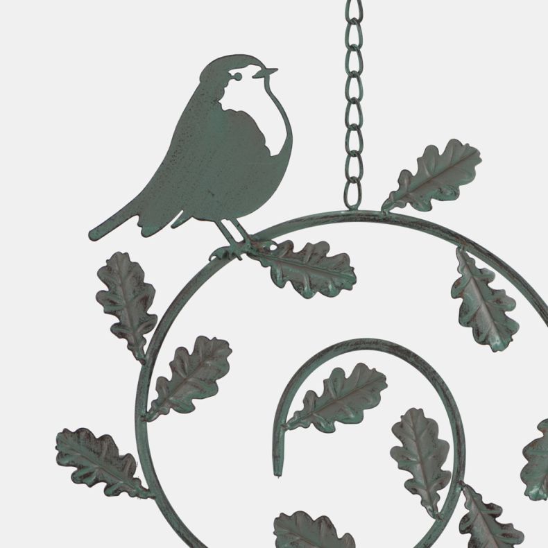 Decorative metal hanging bird feeder detail with perched bird silhouette and oak leaf spiral design in verdigris finish