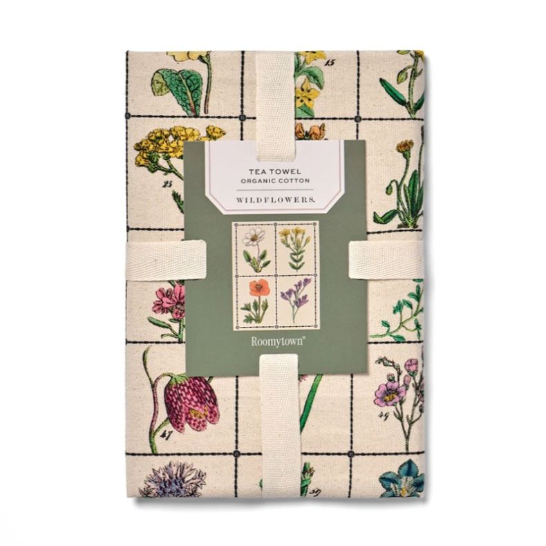 Organic cotton tea towel featuring a vintage-style wildflower illustration print arranged in a grid layout. Folded and secured with a branded paper sleeve, the design showcases colourful botanical drawings on a natural cream background against a plain lig