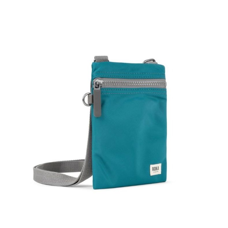 Teal crossbody pouch with a grey shoulder strap, front zip pocket, and ROKA London label.