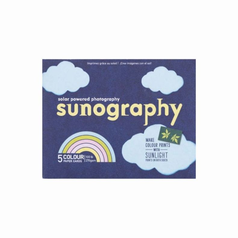 Front packaging of the “Sunography” solar‑powered photography kit, showing a dark blue design with cloud illustrations, the title “sunography,” a rainbow graphic indicating five colour paper cards, and text stating “Make colour prints with sunlight.”