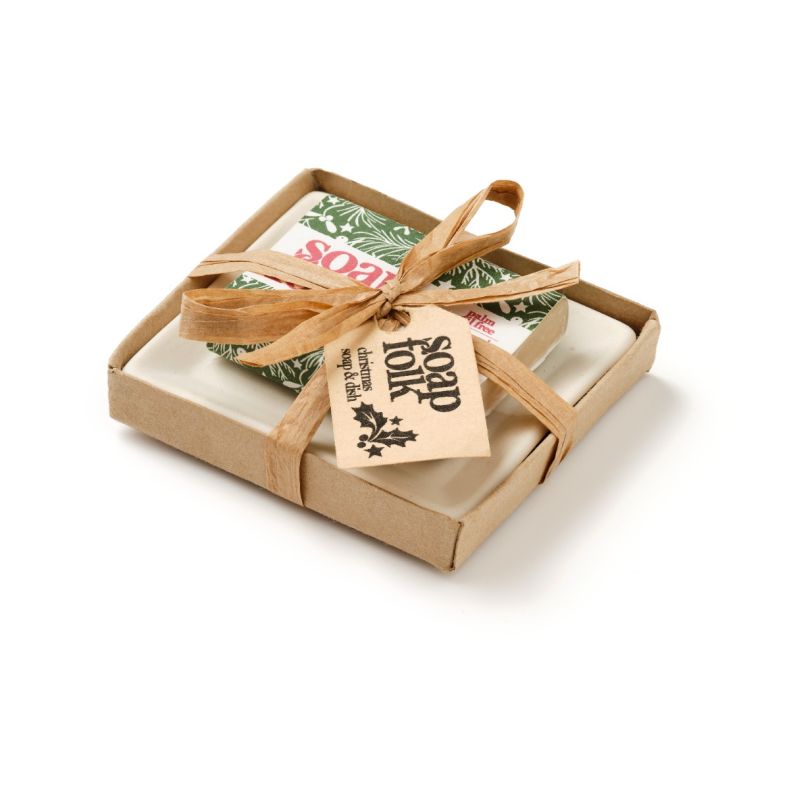 Soap Folk Christmas soap and soap dish gift set, featuring a cream ceramic soap dish and a wrapped Christmas-themed soap bar with green festive packaging, presented in a kraft gift box and tied with a natural ribbon, isolated on a white background.