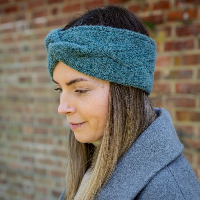 Green and pale mint colour-block knitted gloves with ribbed cuffs, shown worn with a cream knit jumper to highlight the soft textured fabric, contrasting tones and cosy winter styling.