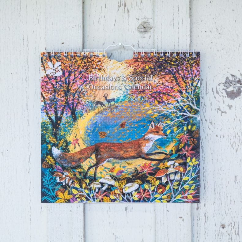 Birthdays & Special Occasions perpetual calendar featuring colourful woodland artwork with a fox walking through an autumn forest, surrounded by vibrant foliage, fallen leaves, mushrooms and trees, displayed hanging against a whitewashed wooden backdrop.