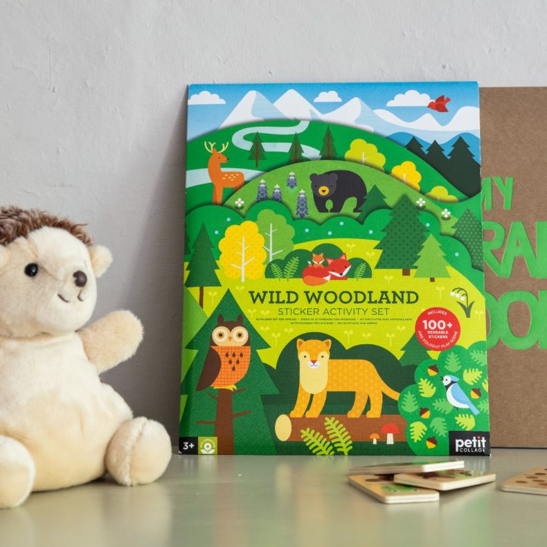 Wild Woodland sticker activity set featuring colourful woodland animal illustrations including a fox, bear, deer, owl and birds, displayed on a nursery shelf alongside a plush hedgehog toy and wooden activity pieces to showcase the nature-themed children'