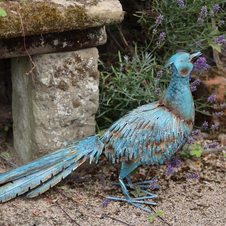 Hand-painted antique metal pheasant garden sculpture with a verdigris finish displayed beside lavender in a garden border.