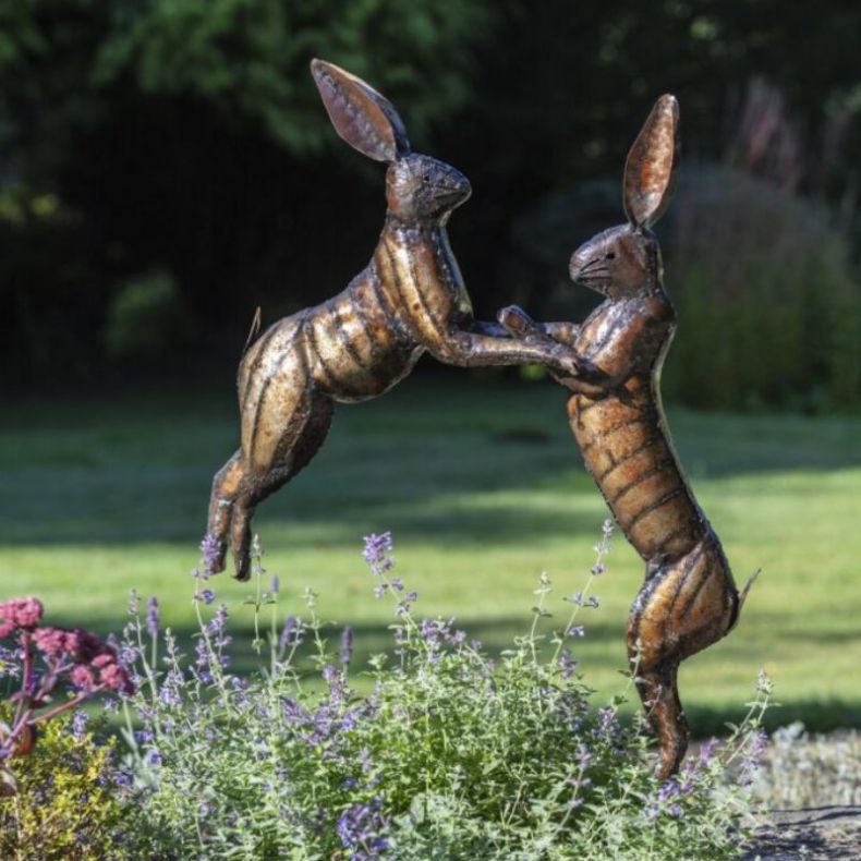 Metal boxing hare ornament and sculpture in a summer garden setting 