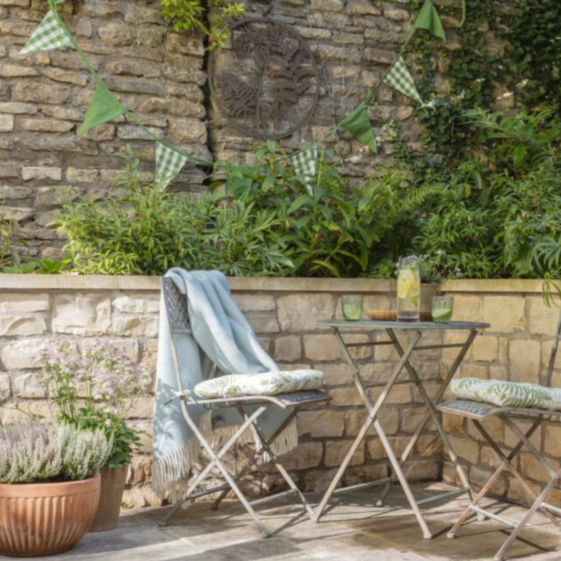 Green bunting in a garden setting with bistro set 