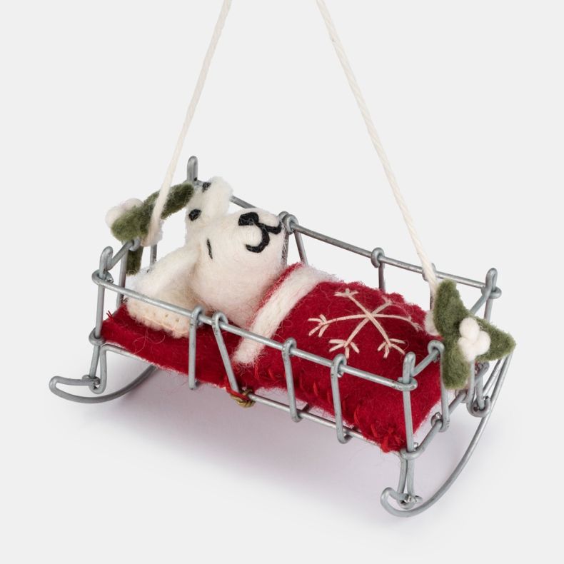 Felt Dalmatian puppy Christmas hanging decoration in a miniature silver-tone wire bed, featuring a white wool-effect puppy with black spots and embroidered facial details, tucked beneath a red felt blanket with white snowflake embroidery and holly leaf ac
