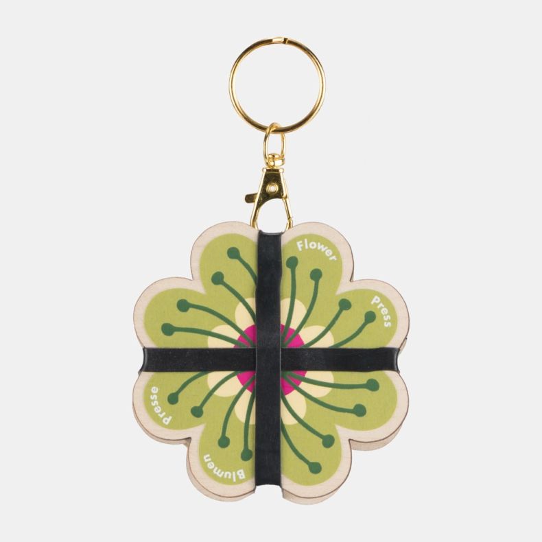 Blumen Pocket Flower Press keyring featuring a flower-shaped design with a vibrant green and pink botanical motif. Crafted from wooden panels with black elastic bands and attached to a gold-tone keyring clasp, this compact flower press is ideal for preser