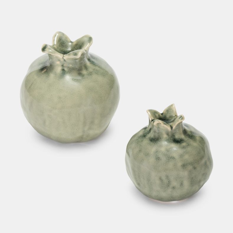 Set of two decorative pomegranate-shaped ceramic ornaments in a soft sage green glaze. Featuring textured detailing and sculpted crowns, the ornaments are displayed in two sizes against a plain light grey background.
