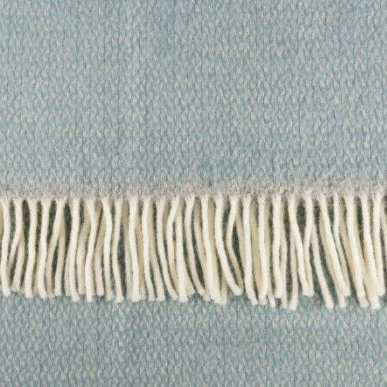 Duck egg blue National Trust woven blanket with a soft texture and white fringe on one edge.