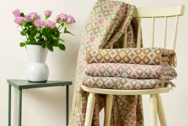 A collection of Bronte wool throws on a white wooden chair