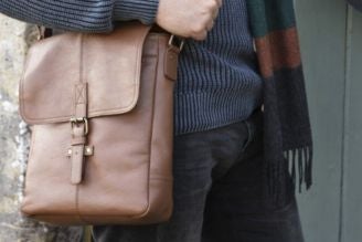 Bags - Woman wearing a National Trust crossbody bag with a colourful floral print, standing in a bright, leafy setting.